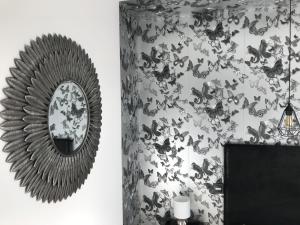 um espelho numa parede ao lado de uma parede coberta de borboletas em Un Moment à la Campagne em Pleuven