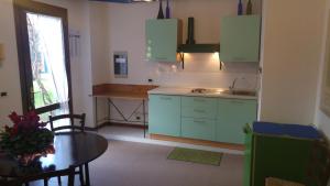 una cocina con armarios verdes, una mesa y una ventana en Dreon B&B, en Portogruaro