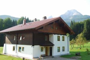 une grande maison blanche avec un toit en bois dans l'établissement Ferienwohnung Familie Schweiger, à Ramsau bei Berchtesgaden