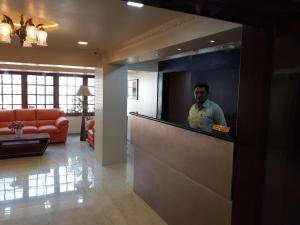 um homem parado atrás de um balcão numa sala de estar em Setrac Orange em Nova Bombaim