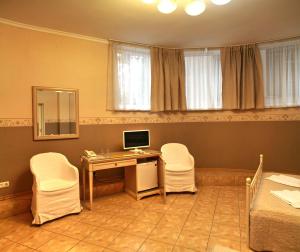 Habitación con escritorio, ordenador y 2 sillas. en Sparta Hotel, en Yalta