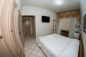 a bedroom with a white bed and a television at Santa Rosa Hotel in Assis