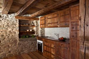 a kitchen with wooden cabinets and a stone wall at Il Fienile della Nonna in Introd