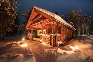 uma cabana de madeira na neve à noite em Lampiranta Log cabin em Hossa