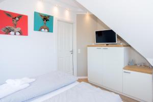 a white bedroom with a bed and a tv at Living-art in Wangerooge