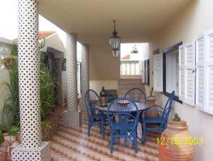a patio with blue chairs and a table on a porch at Villa Sur La Plage in Oualidia