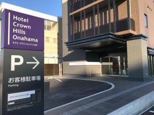 un cartello di fronte a un edificio con parcheggio di Hotel Crown Hills Onahama a Iwaki