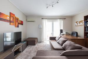 uma sala de estar com um sofá e uma televisão em Holargos Metro Rooms em Atenas