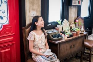 a young girl sitting in a chair holding a cup at Angel Wings Inn in Hualien City