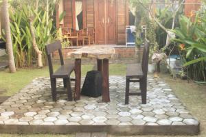 un tavolo in legno e 2 sedie su un patio in pietra di Surya Home Stay a Nusa Lembongan Altre 39 foto