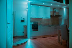 Appartamenti Luxury Arco في آركو: مطبخ مع دواليب بيضاء واضاءة زرقاء