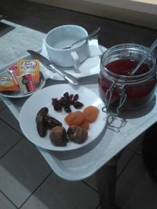 una mesa con un plato de comida y un frasco de mermelada en Logis Hotel L'ange Couronne, en Belleville-sur-Saône