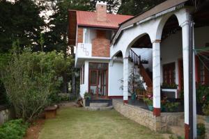 ein weißes Haus mit einem roten Dach und einem Hof in der Unterkunft Cecilia Cottage in Nuwara Eliya