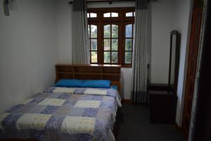 1 dormitorio con cama y ventana en Cecilia Cottage, en Nuwara Eliya