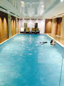 a person swimming in a large swimming pool at Orbi Palace Bakuriani Apartment in Bakuriani