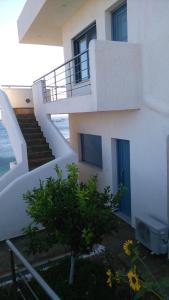 ein weißes Gebäude mit Treppen und einem Baum davor in der Unterkunft Dimitris House in Karystos