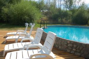 a group of white chairs sitting next to a swimming pool at La Estancia in Trevelin
