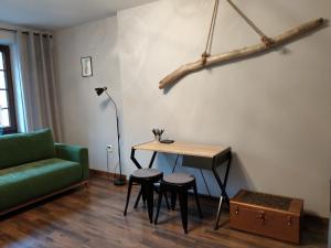 a living room with a table and a green couch at Oficyna Form - Apartament Dwupoziomowy in Elblag
