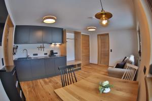 a kitchen and living room with a wooden table and a dining room at Haus am Schihang in Lermoos