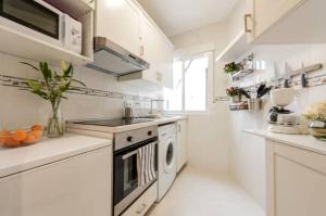 a white kitchen with a stove and a dishwasher at Apartamento en Calle Jardines - Madrid Centro in Madrid