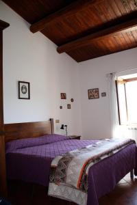 um quarto com uma cama roxa e uma janela em La Locanda del Collaccio em Preci