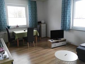 a living room with a tv and a table with a table at Gästehaus Wetzel in Braunlage