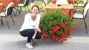 a woman is sitting next to a flower bush at Hotel Duc De Rohan in Livigno