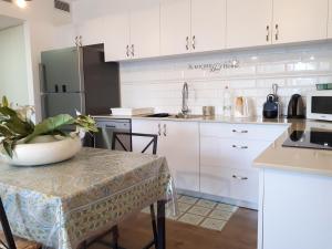 uma cozinha com armários brancos e uma mesa com uma planta em Haneviim Apartment In The Heart Of Jerusalem em Jerusalém