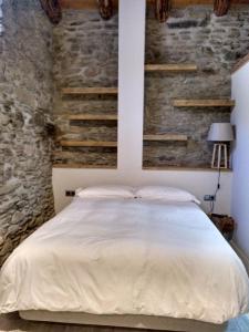 1 dormitorio con 1 cama con pared de piedra en Vilamaroto, en Meranges