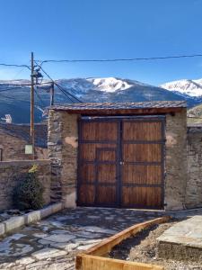a house with a wooden garage door with mountains in the background at Vilamaroto in Meranges