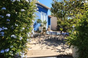 een patio met stoelen en bloemen voor een blauw huis bij Absolument Levant in Île du Levant