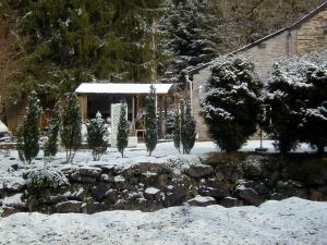 a yard covered in snow with trees and a building at Hotel Ermitage du Moulin Labotte in Haybes