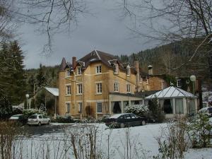 un grand bâtiment en briques avec des voitures garées devant lui dans l'établissement Hotel Ermitage du Moulin Labotte, à Haybes