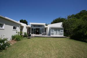 a white house with a lawn in front of it at Home on Plato in Plettenberg Bay