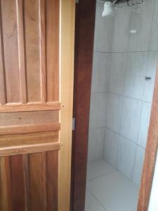 ein Bad mit einer Dusche neben einer Holztür in der Unterkunft Hotel Pousada Guaratuba in Guaratuba