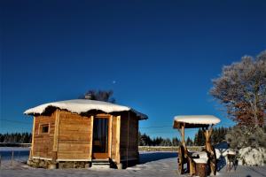 une petite cabane en bois avec de la neige sur le toit dans l'établissement Eco Yourte, à Sembadel