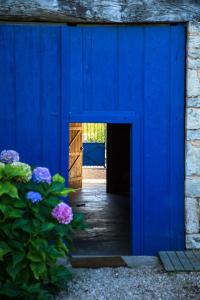 a blue barn with a blue door and purple flowers at Les Portails Bleus in Azé
