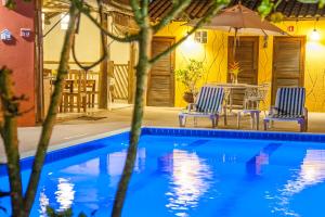 - une piscine avec 2 chaises, une table et un parasol dans l'établissement Pousada Manhã Dourada, à Arraial d'Ajuda