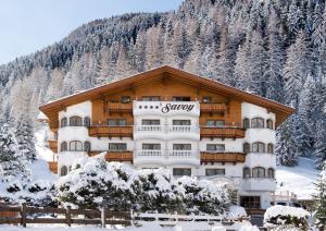 ein großes Gebäude mit einem schneebedeckten Berg in der Unterkunft Savoy Dolomites Luxury & Spa Hotel in Wolkenstein in Gröden