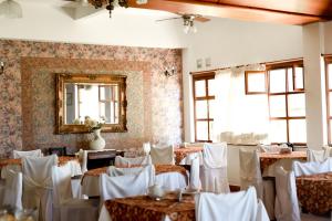 a room with tables and white chairs and a mirror at Hostería Mar de Ajó in Mar de Ajó