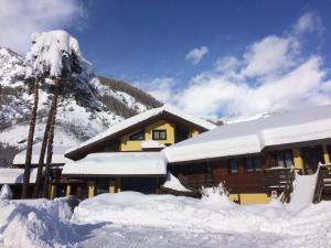 a building covered in snow in front of a mountain at Hotel Cà Fiore in Bardonecchia