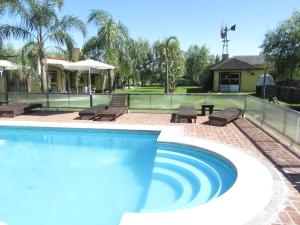 a swimming pool with chairs and a tennis court at Complejo Molino de las Termas in Gualeguaychú