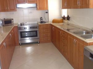 a kitchen with wooden cabinets and a stainless steel stove at Townhouse Ras al Khaimah in Ras al Khaimah