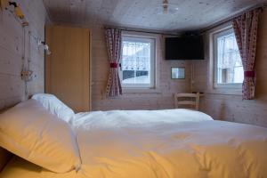 1 dormitorio con 1 cama blanca y 2 ventanas en Zwargji, en Formazza