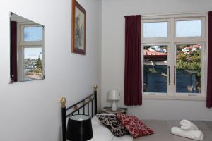 a bedroom with a bed and two windows at Moana Lodge in Plimmerton