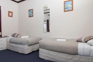 a bedroom with two beds and a ottoman at Moana Lodge in Plimmerton