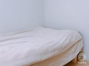 a bed with white sheets on it in a room at Awaza House in Osaka
