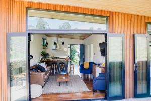 a living room with a sliding glass door at Amongst The Nikau in Waihi Beach