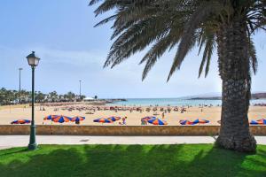 a beach with a lot of people with umbrellas at Canary Islands getaway in Caleta De Fuste