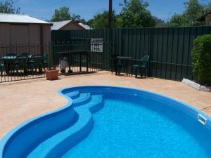 una piscina azul en un patio con una valla en Green Gables Motel, en Dubbo